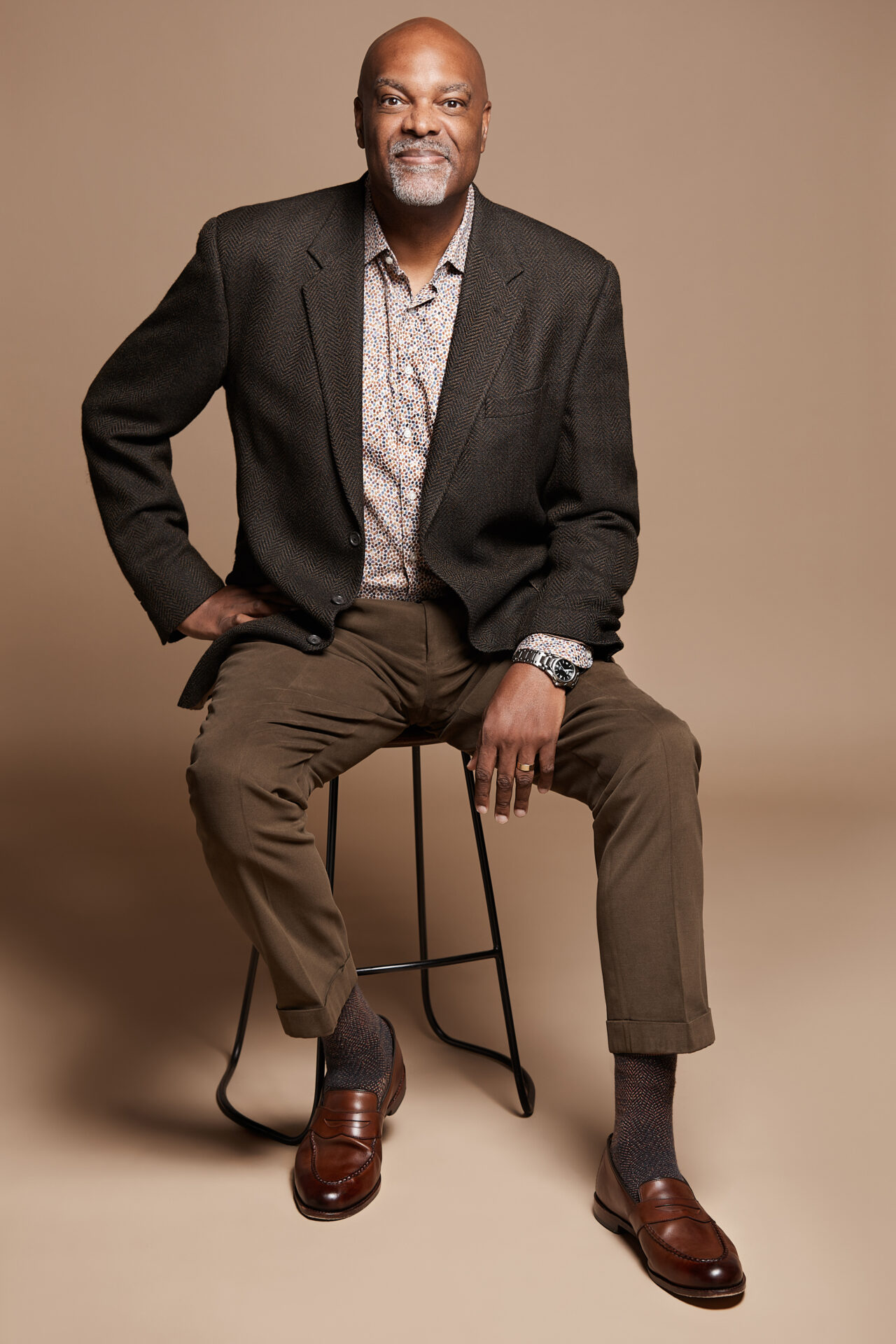 A man sitting on top of a stool wearing a suit.