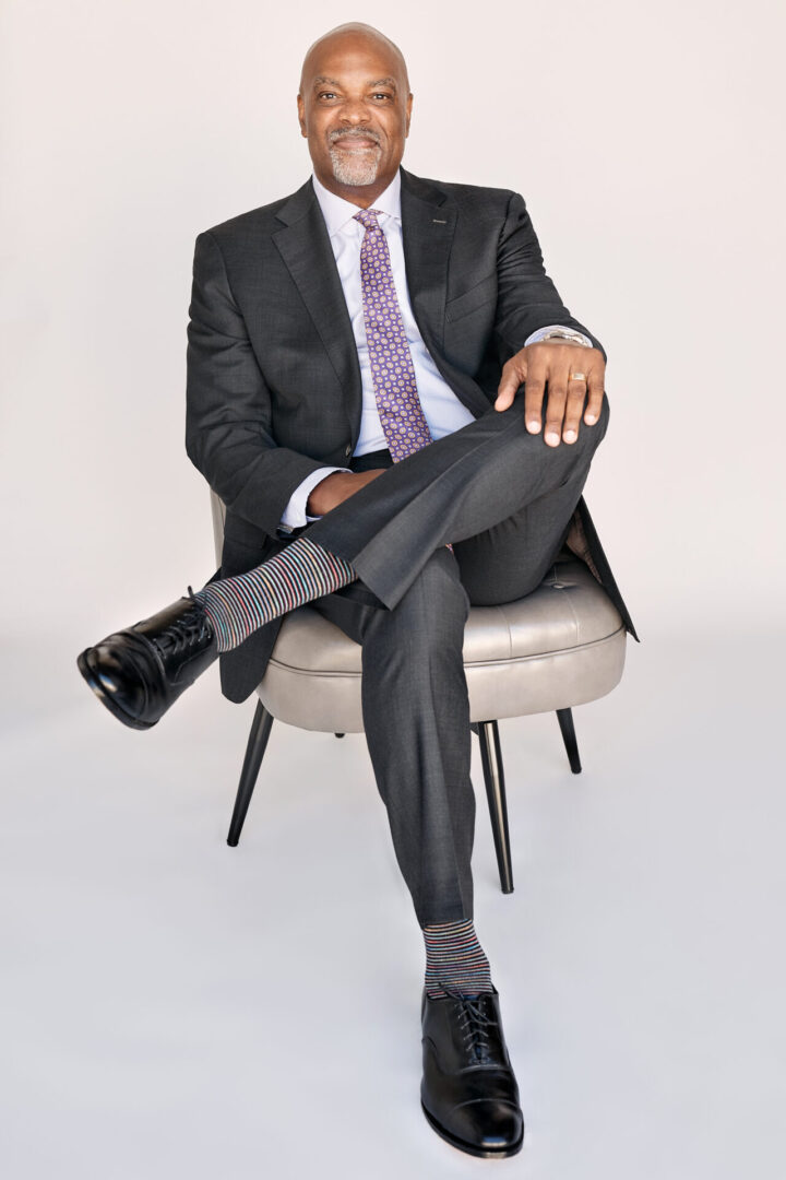 A man in suit and tie sitting on chair.